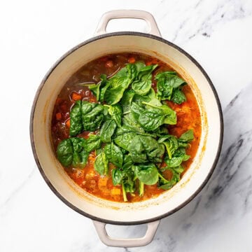 Spinach added to pot of soup.