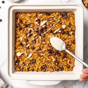 Drizzling cream cheese glaze onto chocolate chip pumpkin baked oatmeal.