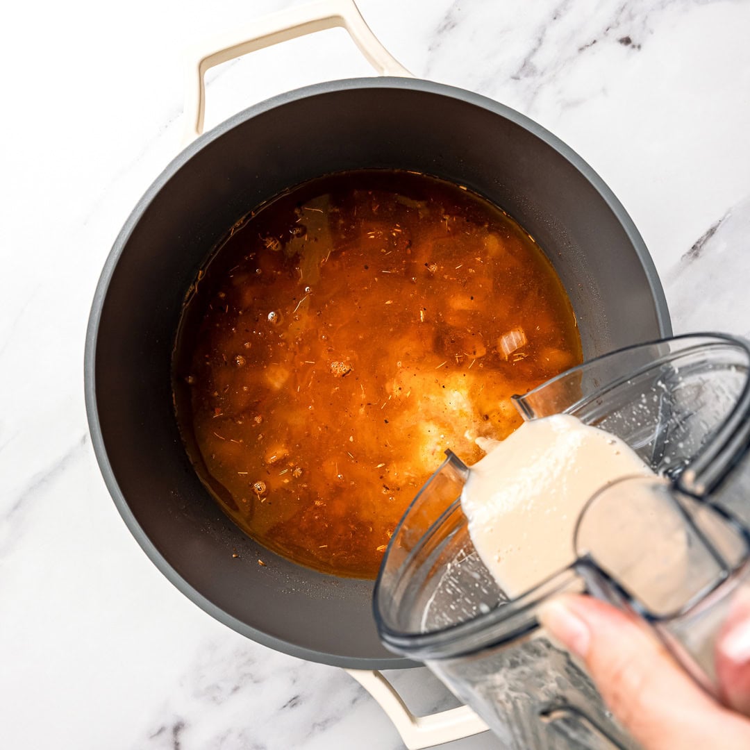 This easy Vegan White Bean Chili is creamy, hearty, and packed with cozy Southwestern-inspired flavors. Tofu adds a satisfying, meaty bite! Pouring pureed white beans into pot of chili.