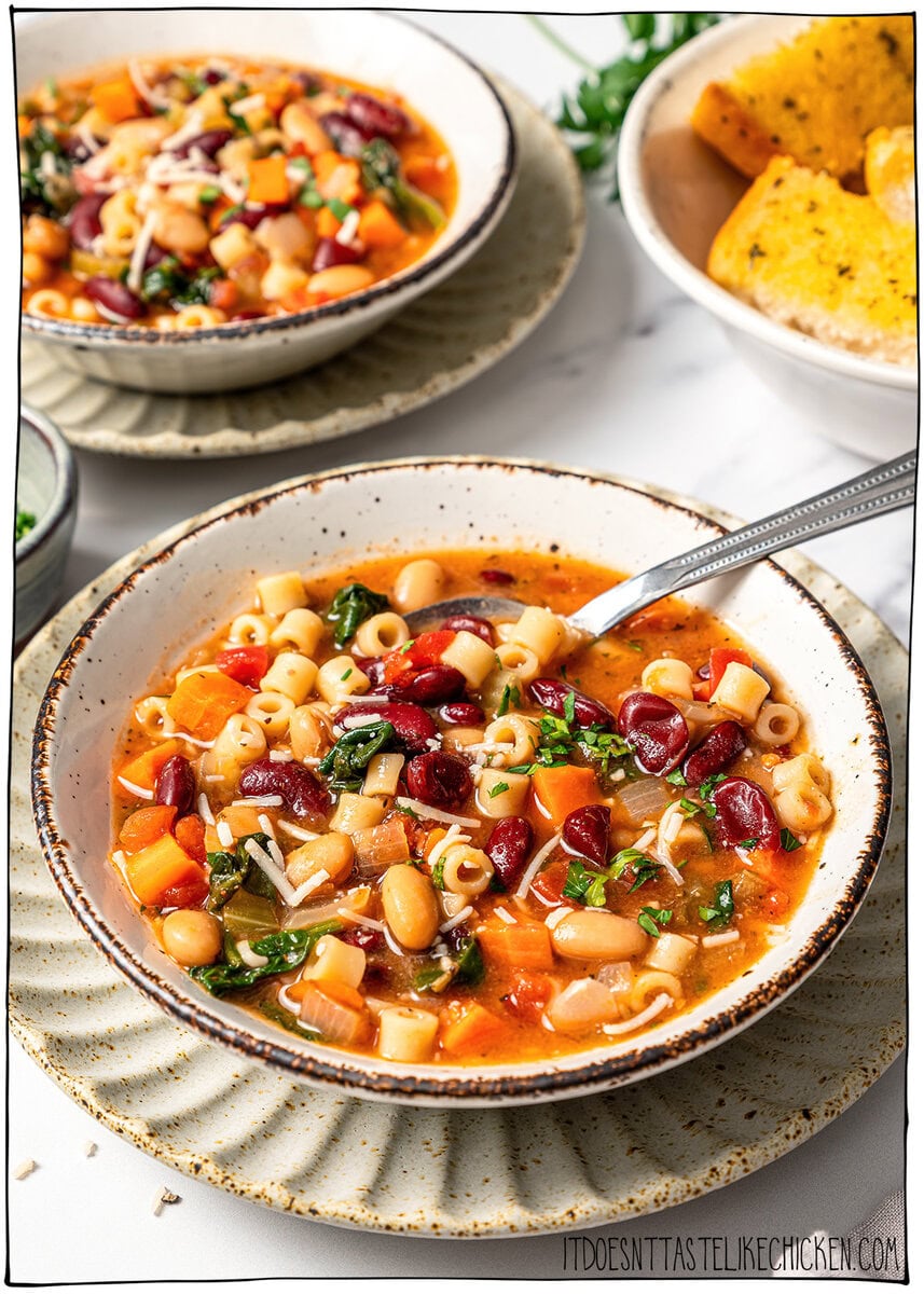 This vegan pasta e fagioli soup is hearty, cozy, and loaded with beans, pasta, and vegetables in a rich tomato broth. A budget-friendly meal! Spoon in bowl of pasta e fagioli soup.